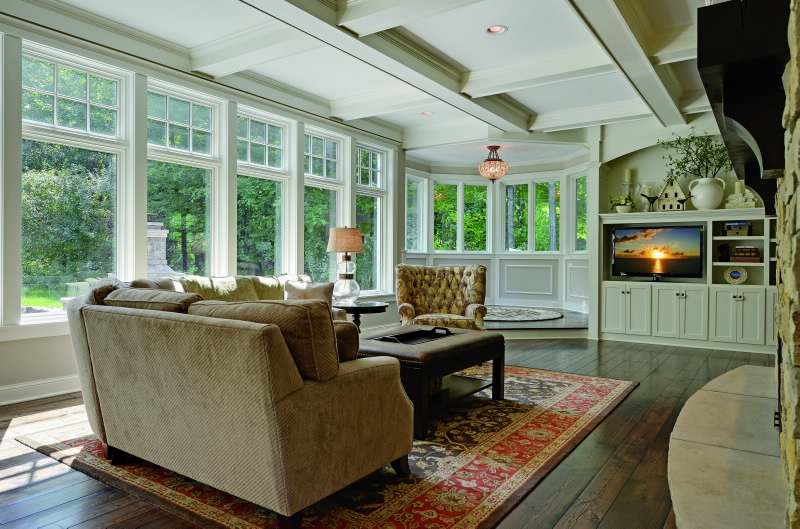 Classic living room with comfortable couch and blanket, television, cabinetry and windows.