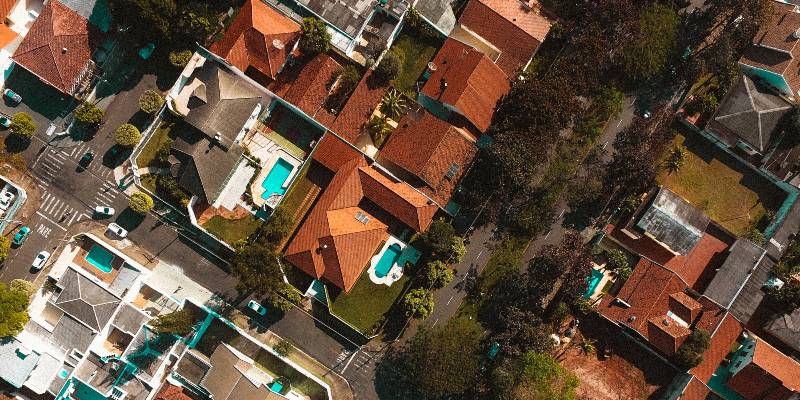 Birds eye view of homes with backyard pools and red roofs.