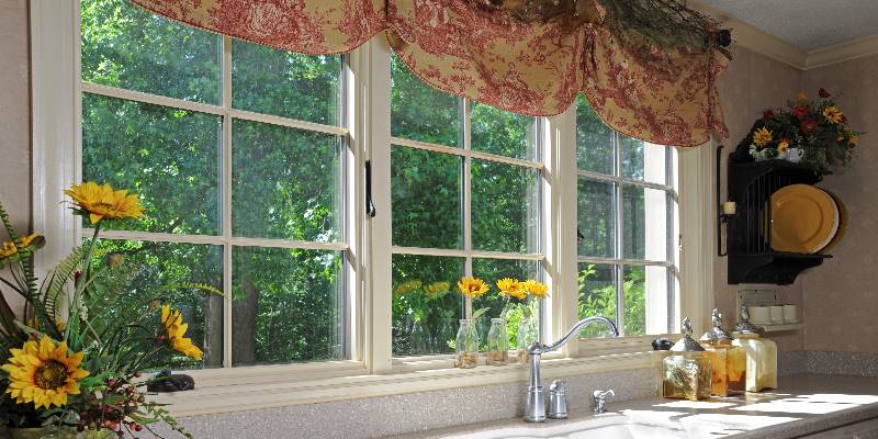 A casement window over a kitchen sink with dandelions.