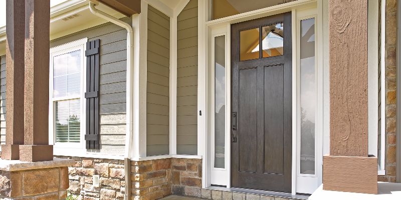 Entryway to home with brown fiberglass door and new siding.