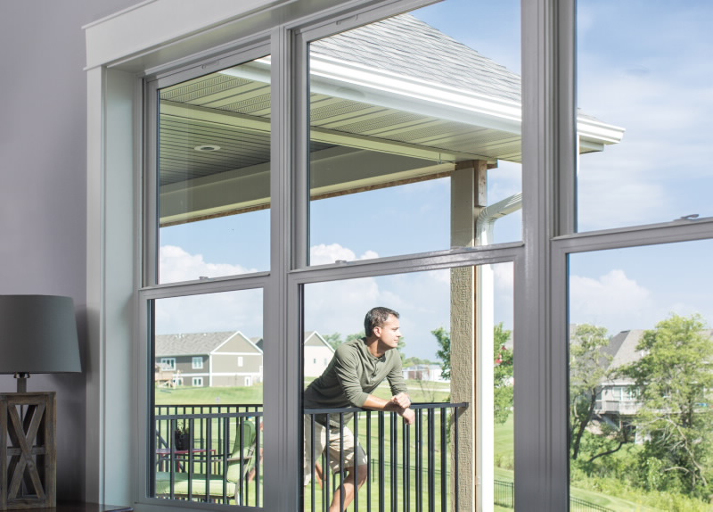 View through massive double hung windows with man in background on porch.