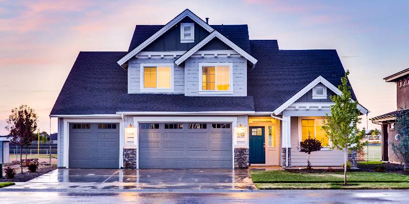 Exterior of large home with lights on and new siding and roofing.