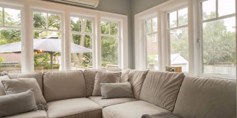 Living room couch with large replacement windows in background.